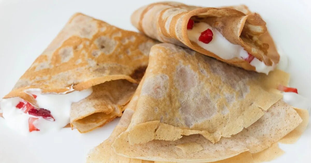 Блинчики на сливках. Блины с клубникой и сливками. блины со взбитыми сливками. исландские блинчики с сливками. ассорти из блинов с начинкой вид сверху.