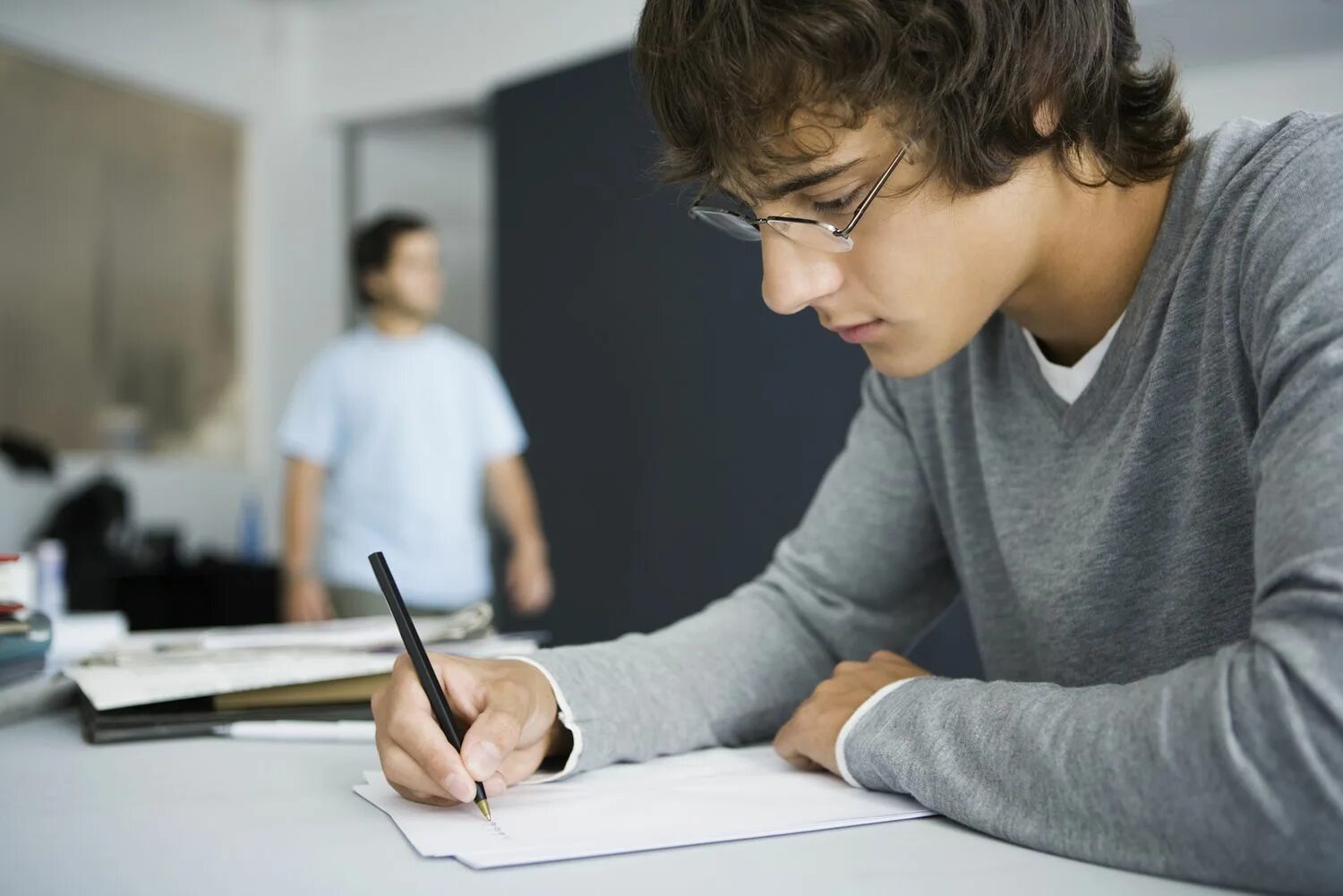 He a student now. Подросток пишет письмо. Человек с тетрадью. Пишущий человек. Человек за тетрадкой.