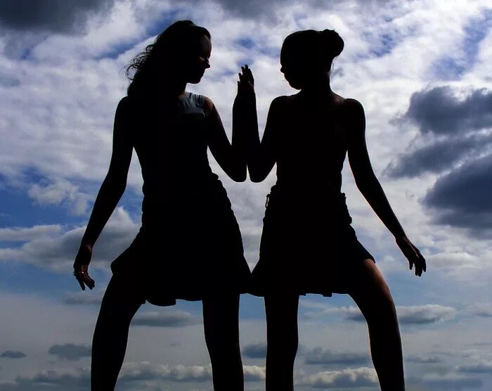 Две девушки спиной друг к другу. Красивые подруги. Подруги спина к спине. Две молодые женщины. Подруги на закате.