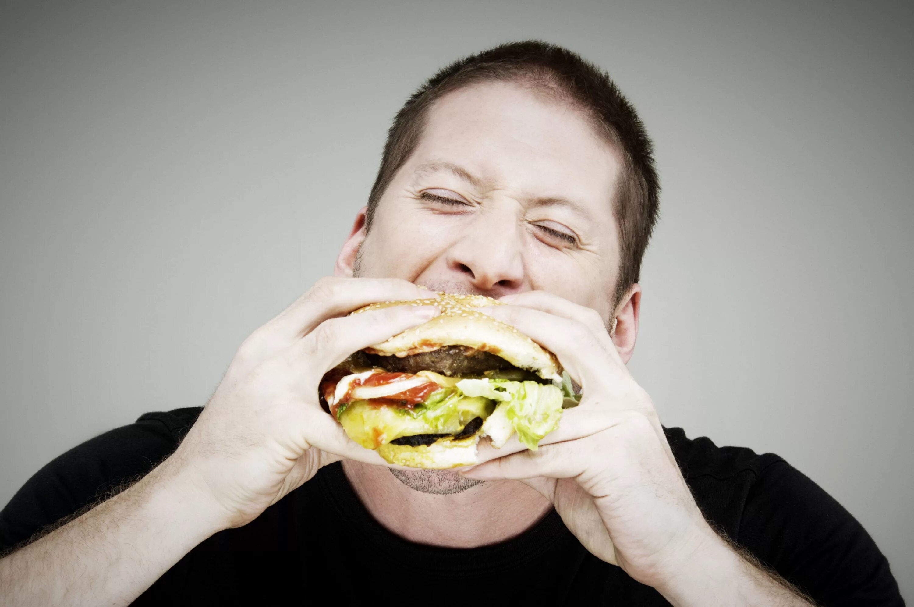 Где едят людей. Человек ест гамбургер. Мужчина ест гамбургер. Человек ест фаст фуд. Человек с бургером.