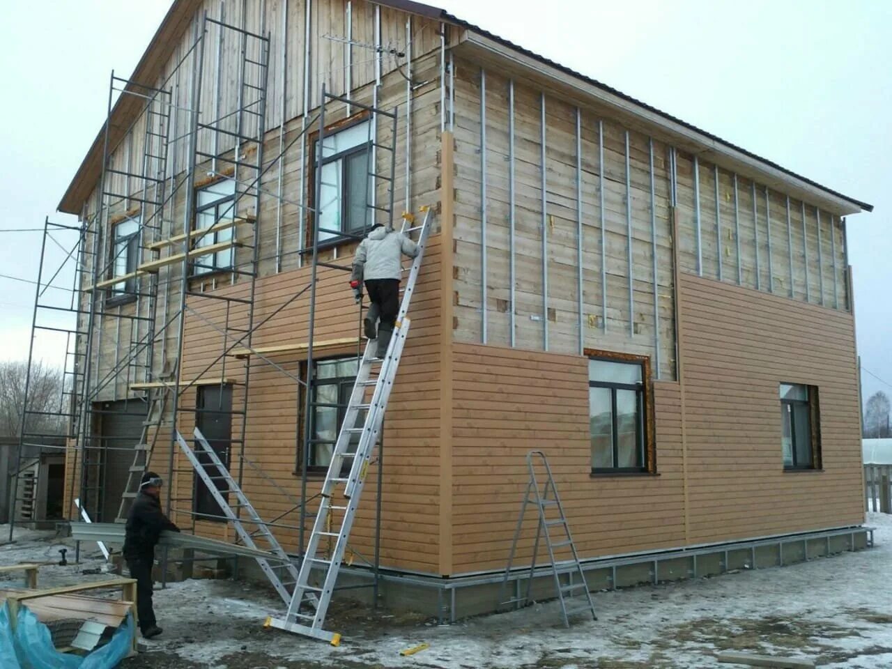 мокрый фасад. строительные леса. строящийся частный дом. вентилируемые фасады многоэтажных домов. покраска фасада многоквартирного дома.