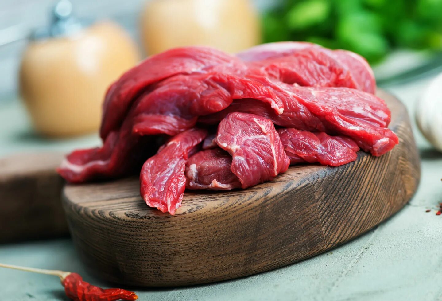 Сырое мясо оленины на столе. Красная доска для мяса.