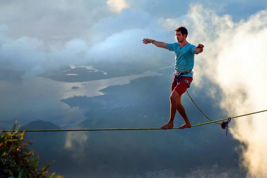 Слэклайн над Рио-де-Жанейро. Человек на канате. Канатоходец над пропастью. Человек идет по канату. Шагая по канату
