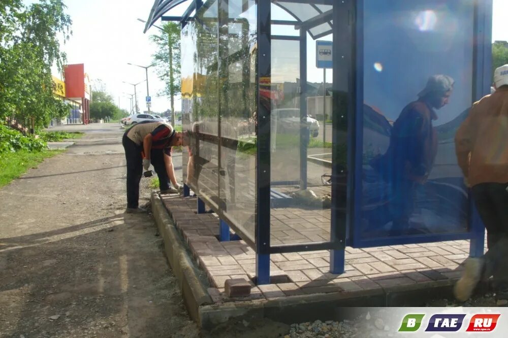 Остановка кипеть. Тротуарная плитка на автобусных остановках. Брусчатка на остановке. За стеклом строители павильона. Тротуарная плитка на автобусных остановках в Европе.