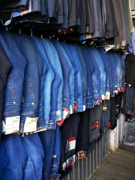 крашение джинсов в промышленных условиях. магазин джинсов. джинсы на вешалке. джинсы с рынка. в новом магазине был большой выбор джинсы.