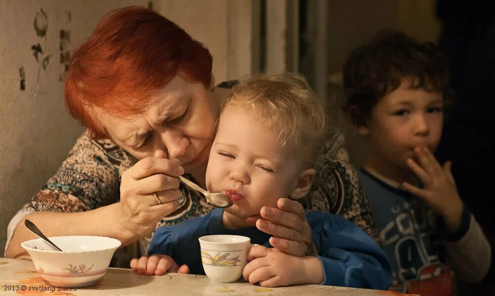 Бабушка и внуки. Бабушка и внук за столом. Бабушка кормит внука. Родители закармливают ребенка. Бабушка хочет мальчика