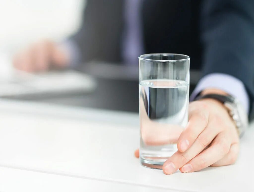 Питьевая вода сотрудников. Вода в офисе. Стакан воды в офисе. Пьет воду в офисе. Стакан воды на столе.