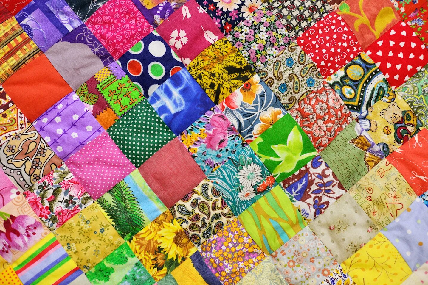 Пестрая ткань. Одеяло из разноцветных лоскутков. Ткань в стиле пэчворк. Разноцветные лоскуты ткани. Полотно из разноцветных лоскутков.