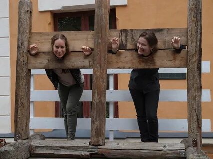 Two young women, playfully locked in stocks or pillory at the Turku Medieva...