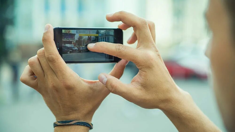 Рука держит фотоаппарат. Люди снимающие на телефоны беду. Рука держит видеокамеру.