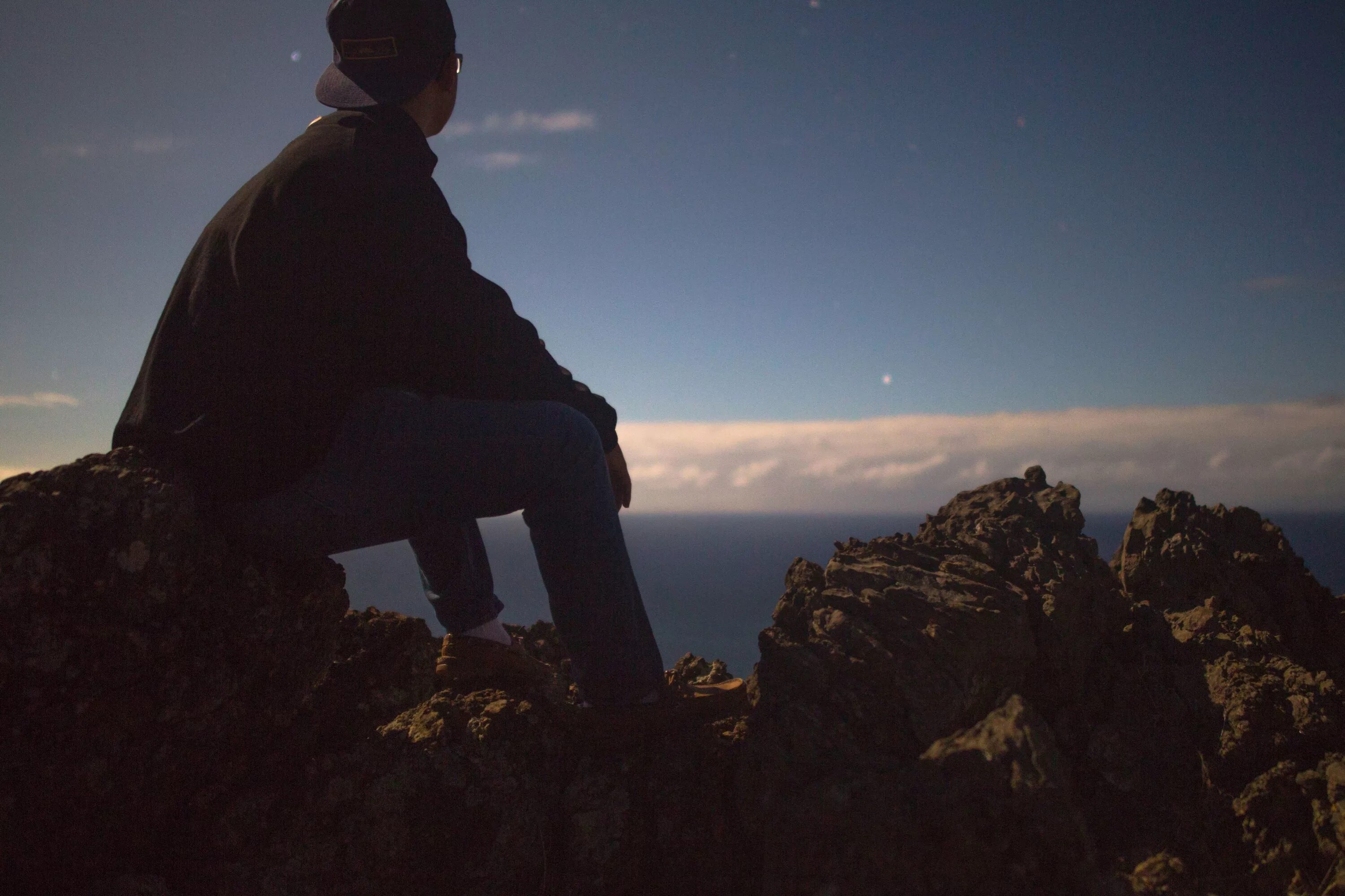 Человек на закате. Мужчина стоящий спиной. Парень сидит на скале. Человек смотрит вдаль. Стою и смотрю в даль.