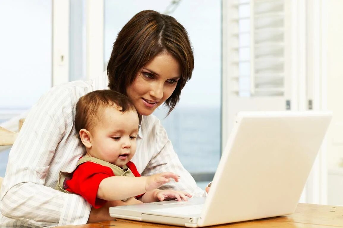 Женщина с ребенком за компьютером. Удаленная работа для мам. Девушка с ребенком у компьютера.