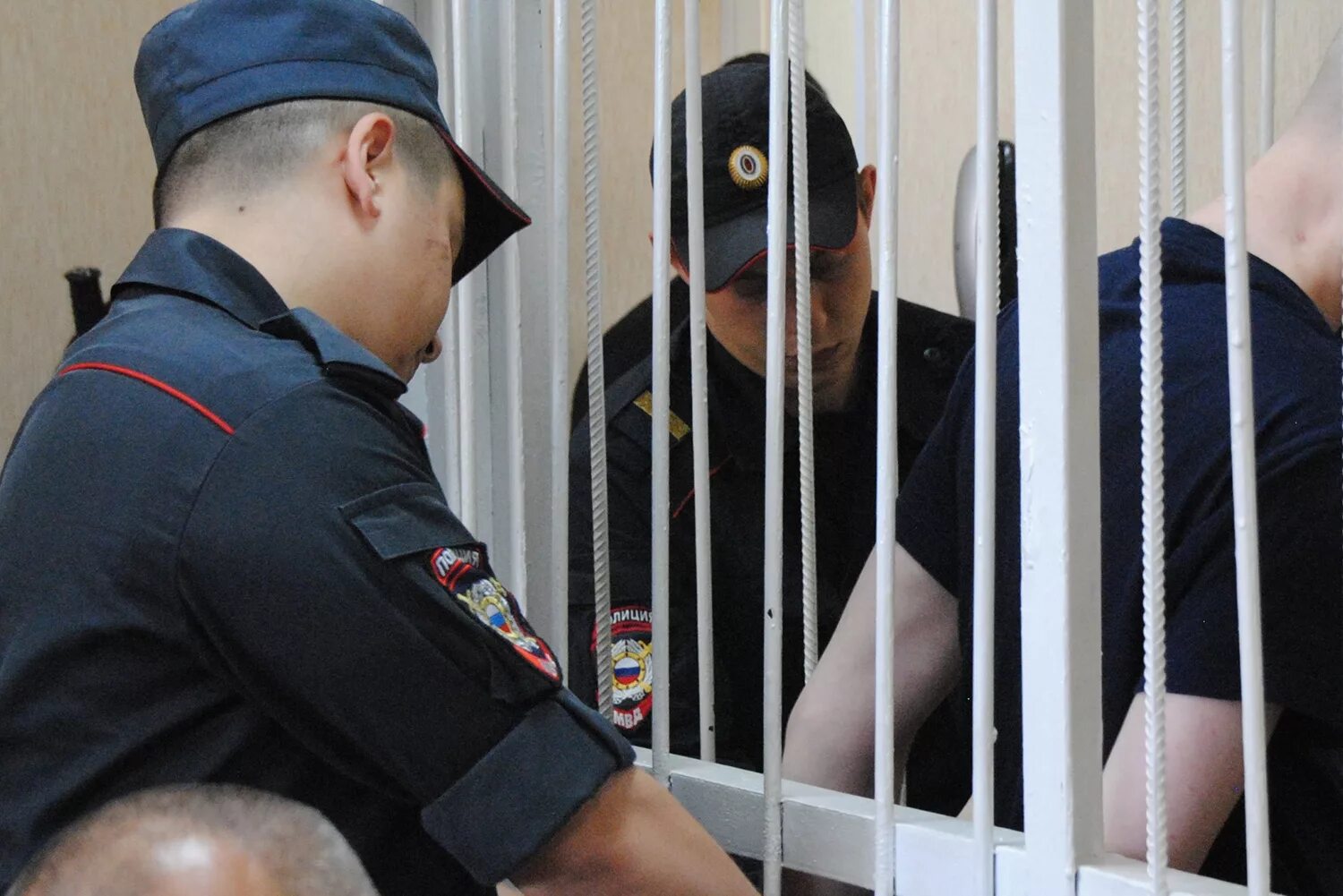 Подсудимый ст. Полицейский за решеткой. подсудимый в суде. осужденный в суде. преступник за решеткой в суде.