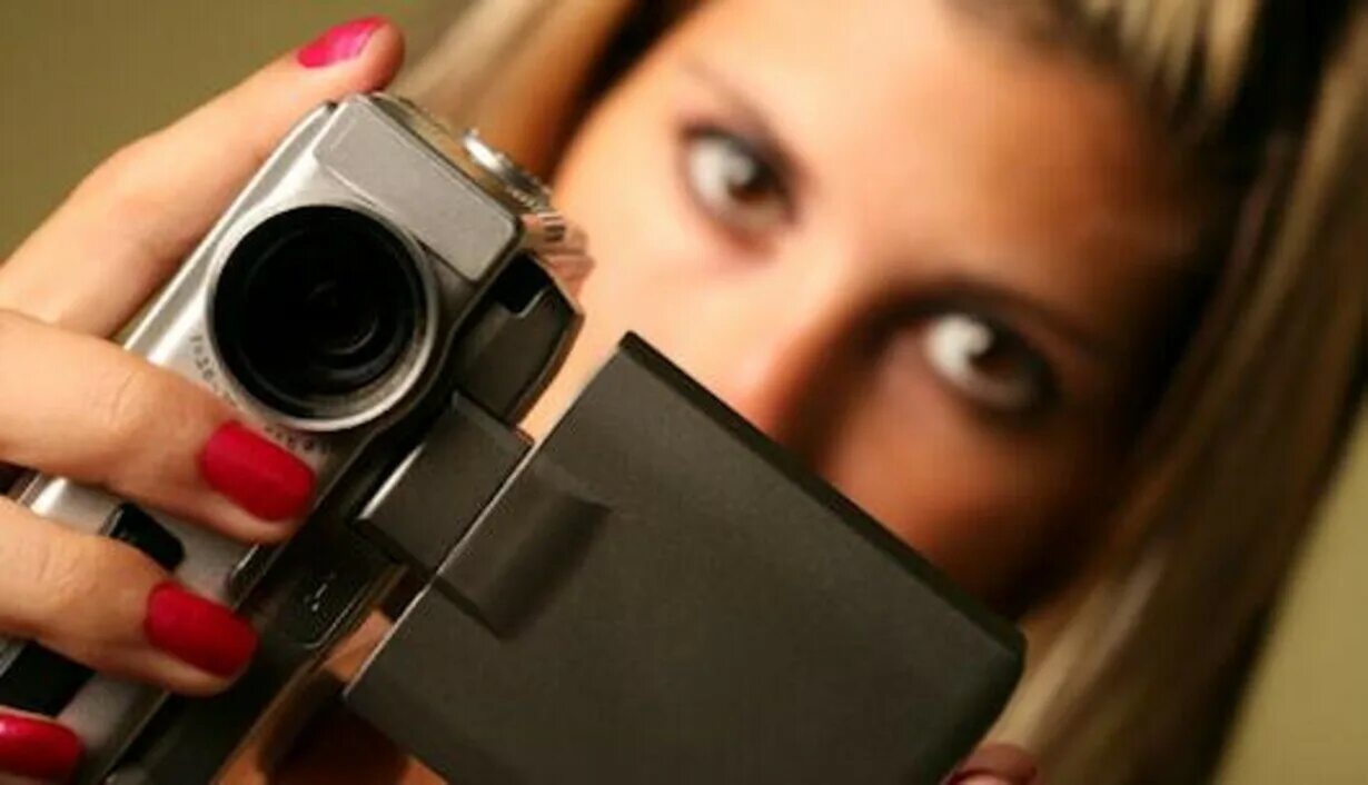 Девушка держит кинокамеру. Видеокамера до 50000 рублей. Снимать видео. Видеоролики.