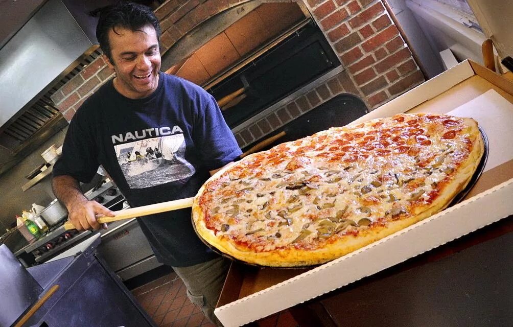 Сколько глав в пицце. Огромная пицца. Американская пиццерия. Пицца в пиццерии. Огромная вкусная пицца.