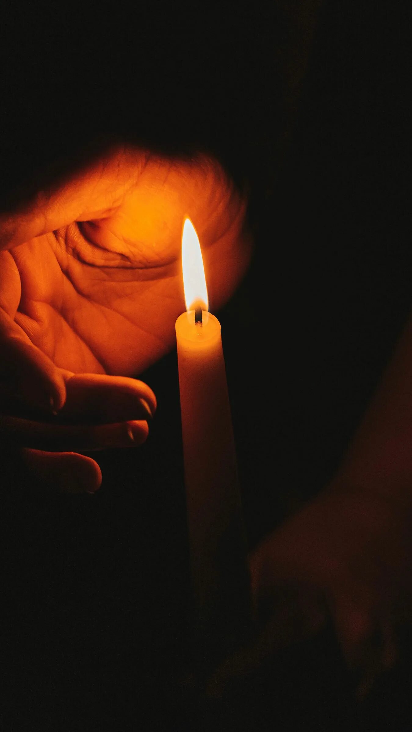 Поминальная свеча. Свеча памяти. Зажженная свеча. Поминальная свеча в ладонях. Зажженная свеча в руках.
