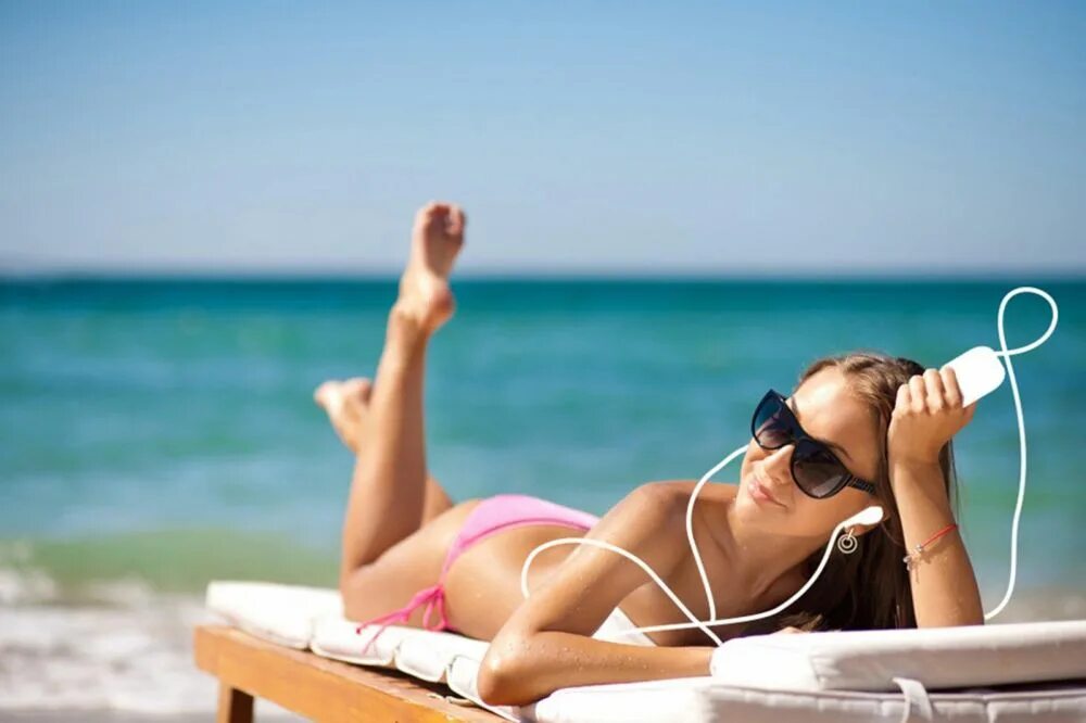 Повседневный отдых. Девушка на пляже на лежаке. Солнце пляж загар. Девушка в шезлонге на пляже. Лежит на пляже.
