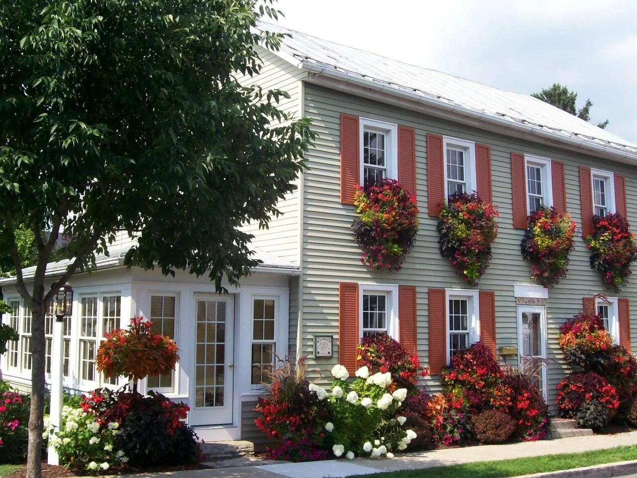 Фасад дома с цветами. Домик украшенный цветами. Красивый дом в цветах. Дом украшенный цветами. Цветочные балкончики италии.