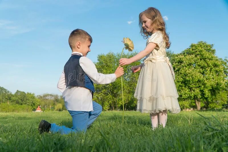 Девочка дарит подарок. Ребенку дарят игрушку. Маленький мальчик дарит цветы. Мальчику подарили девочку осязателя. Маленький мальчик дарит цветы девочке.
