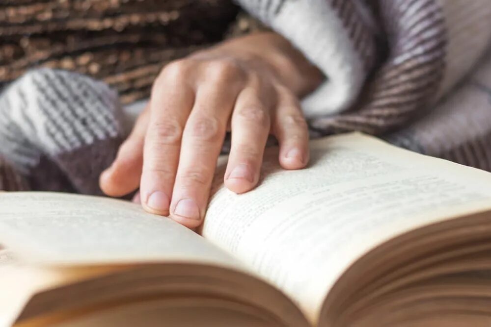Читать книгу без рук. Рука лежит на книге. пожилая женщина с книгой в руках. человек лежит с книгой на руках. протяну за книжкой руку..
