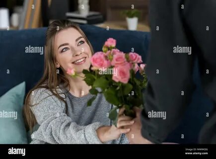cropped image of boyfriend presenting bouquet of roses to girlfriend on internat