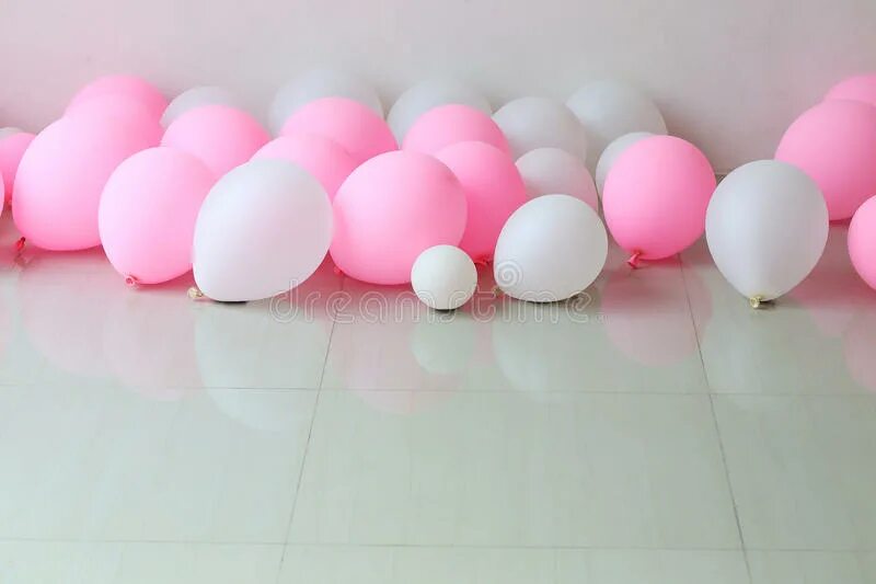 Шары расположены в форме треугольника. Шарики лежачие. Розовый подиум с белыми шарами. Белые воздушные шары на фоне белой стены. Шарик воздушный лежит.